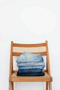 A pile of jeans placed on a chair for sorting through later.