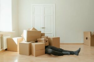 A person buried under a pile of boxes, tired during their packing and moving.