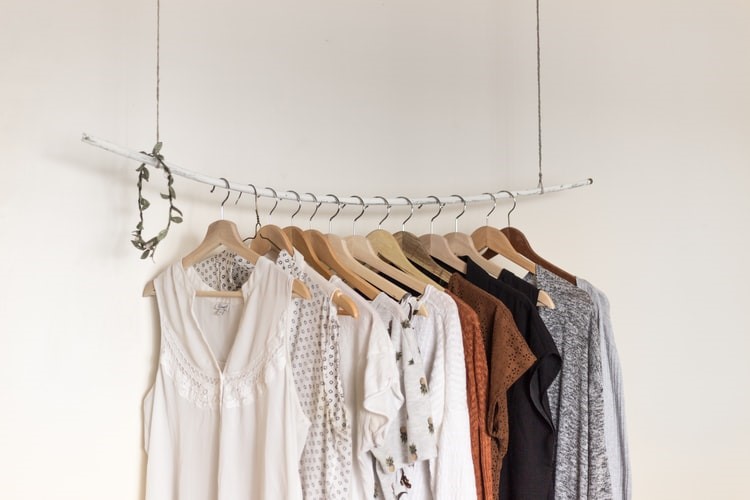 A rack with various shirts and tops hanging over it.