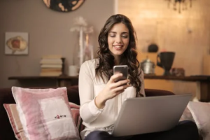 a woman using a laptop and smartphone